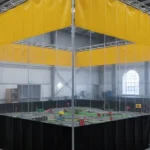 Yellow-topped modular curtain RCdrone course – “Indoor RCdrone course enclosed with modular curtain walls with yellow top panels and black lower panels, showing flexible layout and safety zones.