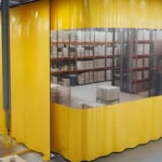 Yellow vinyl curtain enclosure with clear viewing panels separating glazing shelves from the main clay workspace
