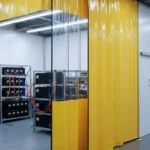 Yellow vinyl curtain setup with clear panels used to isolate an active battery-testing area in an EV lab
