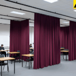 Academic testing room with burgundy curtains creating individual student exam stations