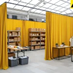 Bright fabric curtain walls dividing inventory storage from the customer-facing floor in a pop-up shop