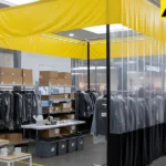 Clear vinyl curtain enclosure separating backstock and staff staging area from shoppers in a pop-up boutique