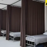 Dark fabric curtains providing privacy between beds in shared living quarters