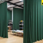 Dark fabric loft divider curtains organizing a creative studio with exposed ceilings and open layout