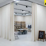 Neutral fabric curtains forming a private backstock area within a shopping mall pop-up shop