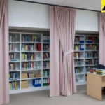 School or office shelving concealed with soft pink closet and alcove cover curtains