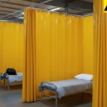 Yellow curtain dividers creating individual sleeping spaces in shared housing