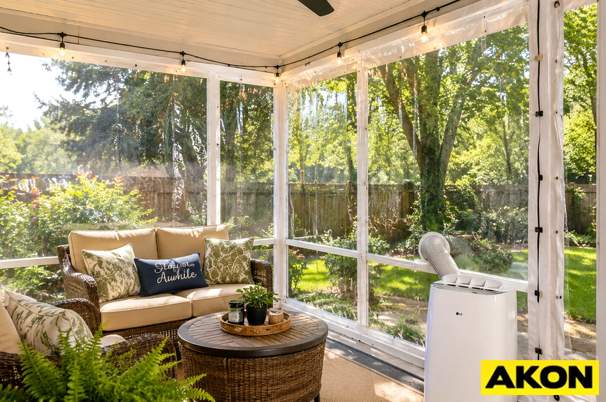 A portable air conditioner set up on a screened porch with a curtain enclosure to retain cooled air.
